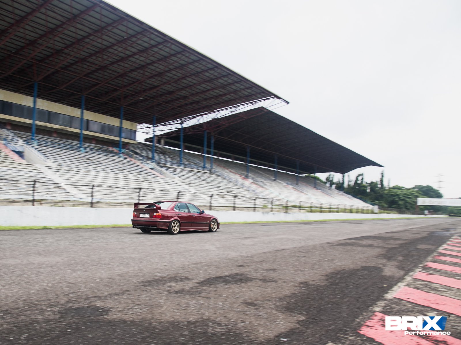 BMW E36 driving on circuit, showcasing stance and motion with BRIX Performance.