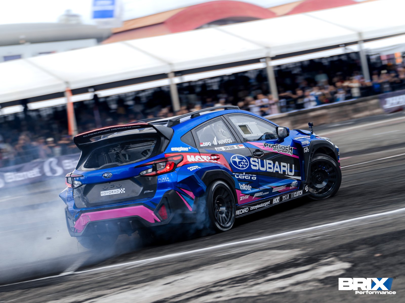 Rear view of Subaru Crosstrek initiating drift with tire smoke during Southeast Asia Drift Series.